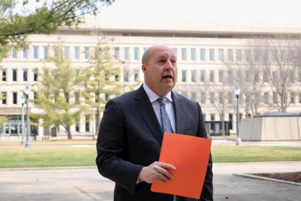 Curtis Hertel, candidate for Co<em></em>ngress in Michigan's 7th District, dressed in a suit and holding an orange file