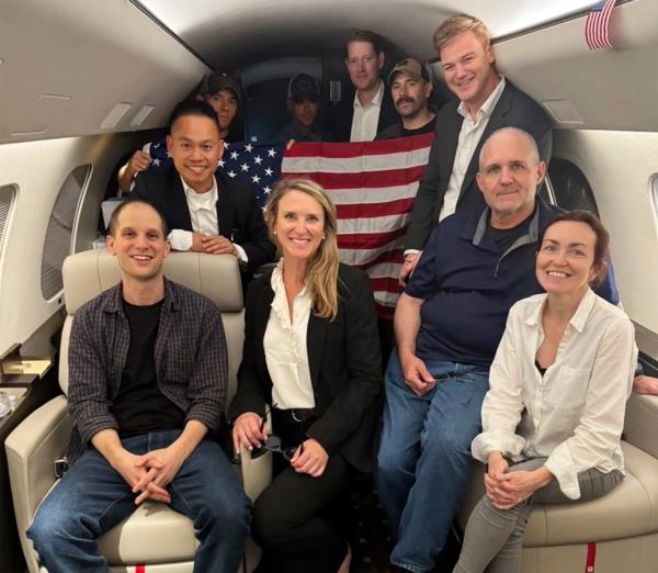 Evan Gershkovich, left, Alsu Kurmasheva, right, and Paul Whelan, second from right, and others aboard a plane.