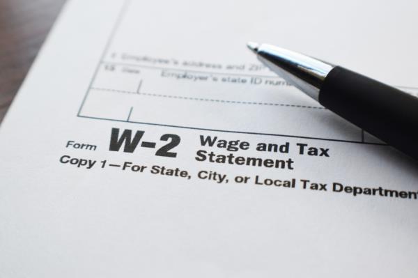 A close up of Form W-2 Wage and Tax Statement, with a black and silver pen sitting on top.